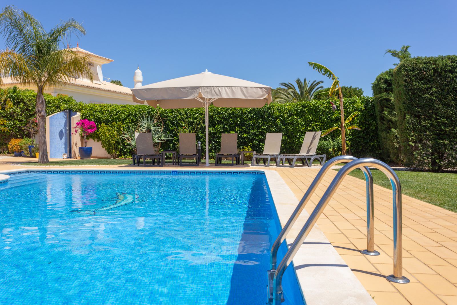 Clean and well-maintained residential swimming pool with lounge chairs and patio area in Brentwood CA